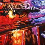 Neon lights on a rainy night create an abstract piece of art of a street curb and a manhole cover in red, pink, yellow, and purple