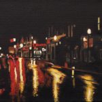Red traffic lights on a downtown Peterborough street; the wet pavement reflects red and creamy white lights